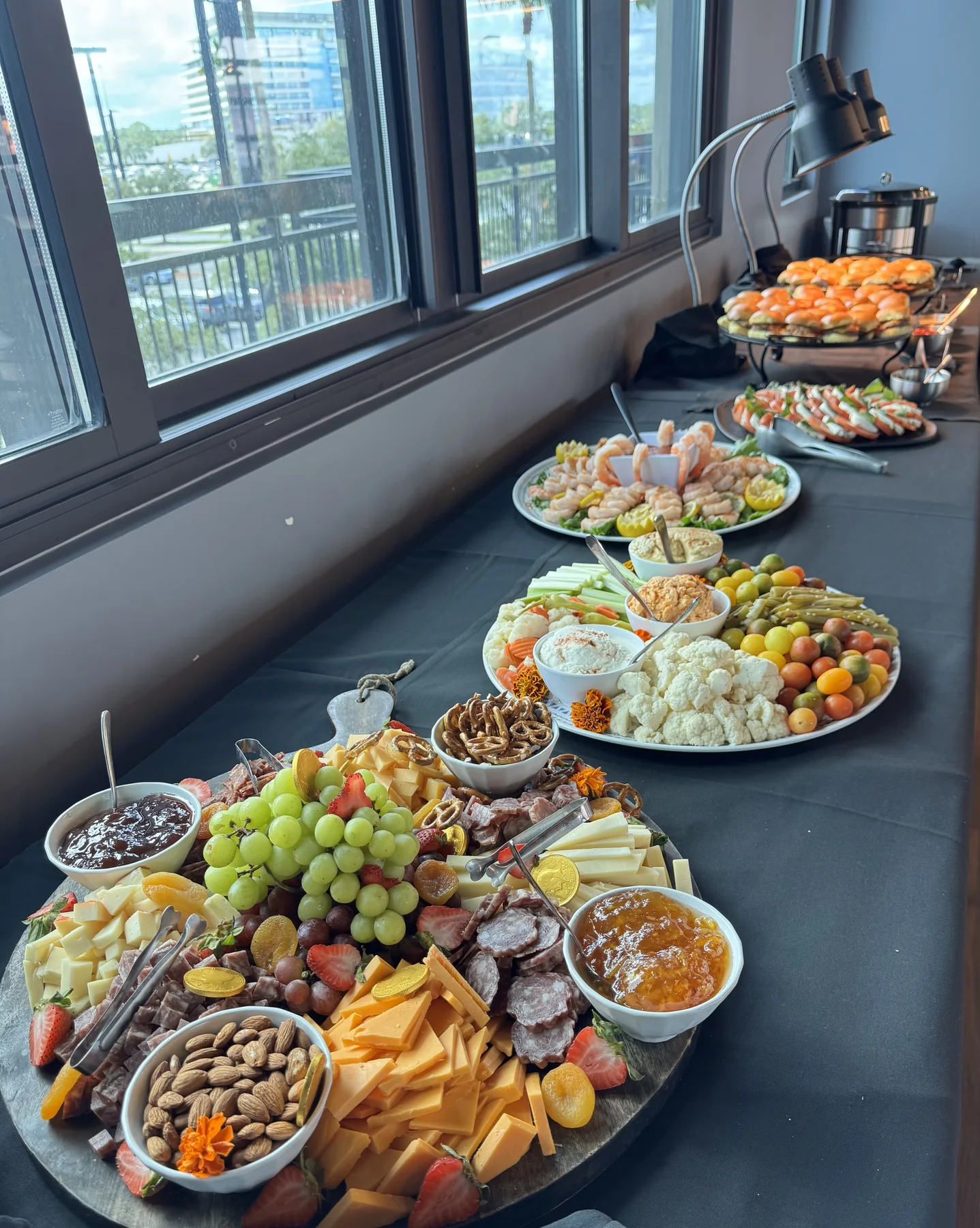 Appetizer buffet with charcuterie, vegetables, shrimp and sliders